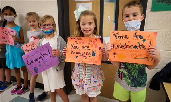 Students hold up signs for graduating seniors